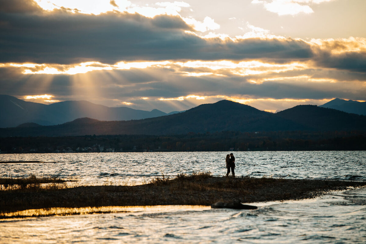couple kissing on lake champlain at sunset mountain views with sunlight