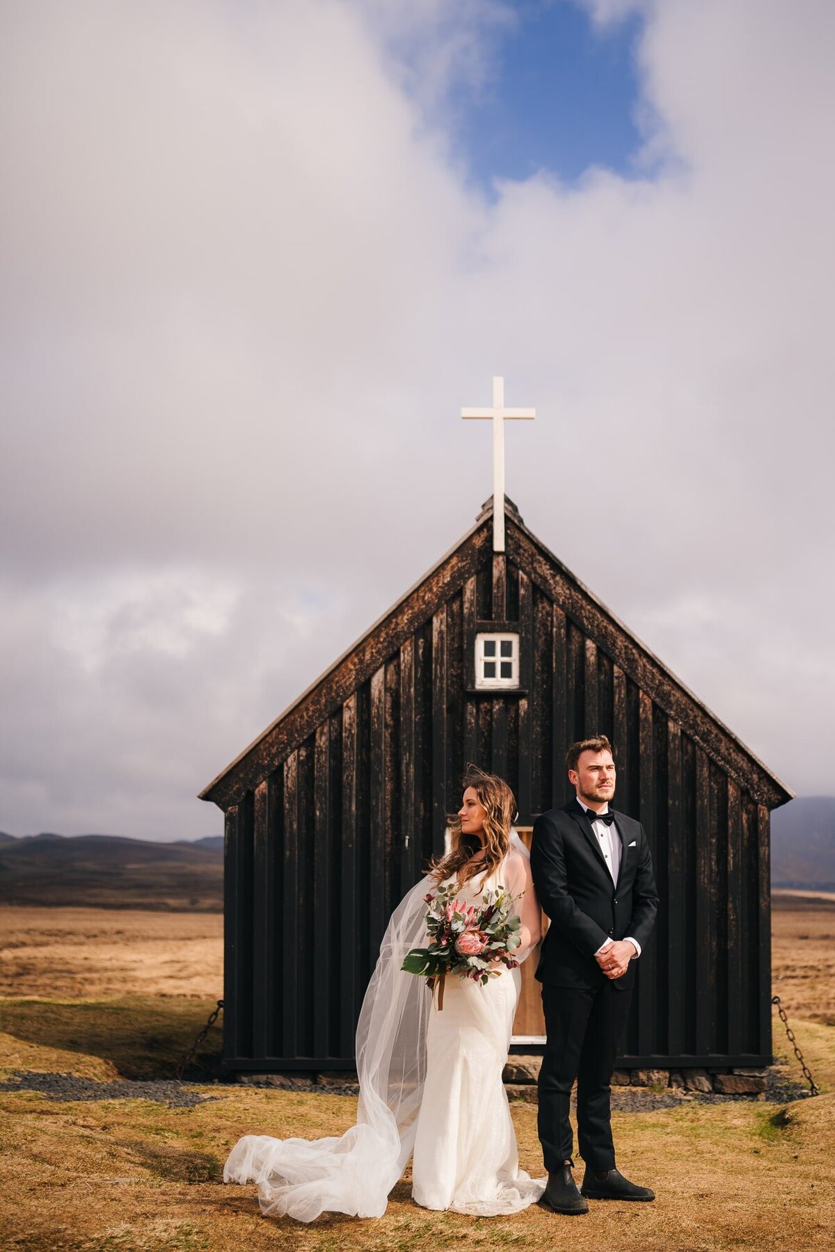 This couple stands facing opposite horizons, a quaint Icelandic church as their silent witness, surrounded by the breathtaking scenery that adds to the magic of their love story.