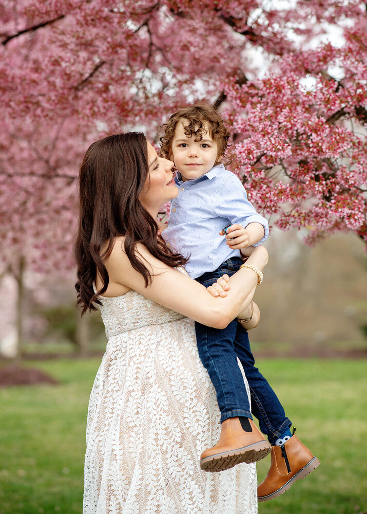 Family session of little boy and his mother under flowers