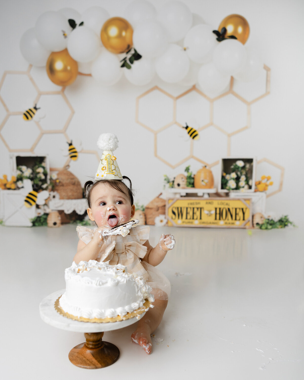 Adorable little one tasting every bit of her bee-themed birthday cake, surrounded by sweet honey details and golden giggles. Captured by Yucaipa cake smash photographer Kaitlyn Dawn Photography.