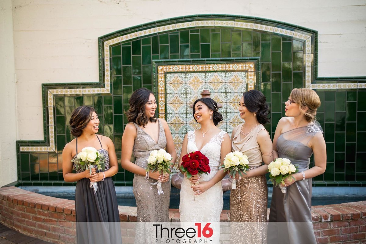 Bride and her Bridesmaids together in front of a wall fountain