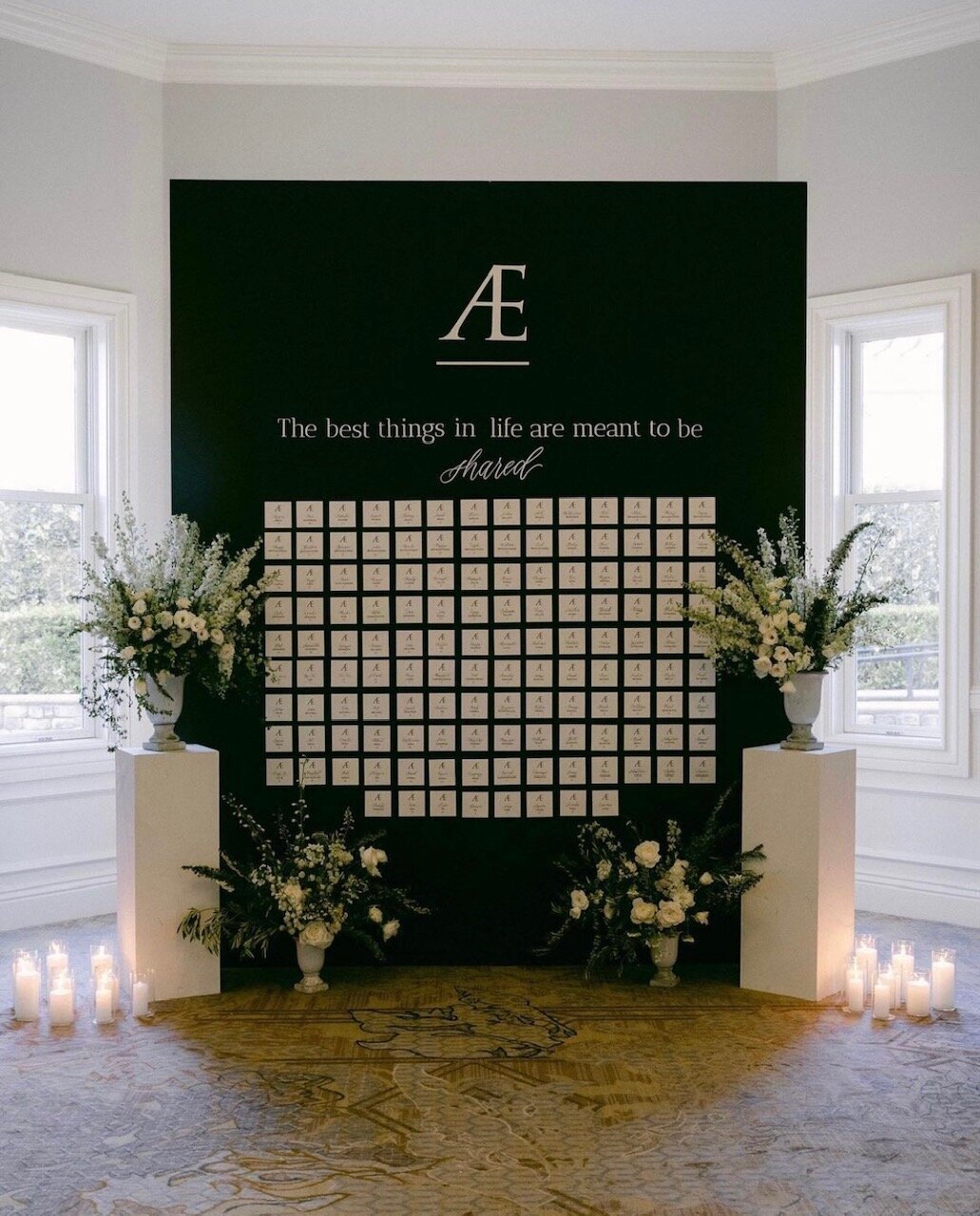 Tall black wall with individual escort cards, surrounded by florals for a black and white wedding