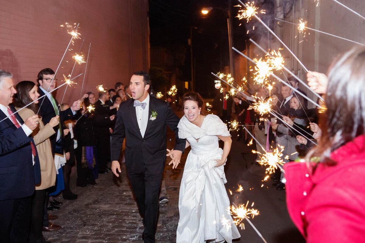 a happy couple exit their wedding surrounded by sparklers