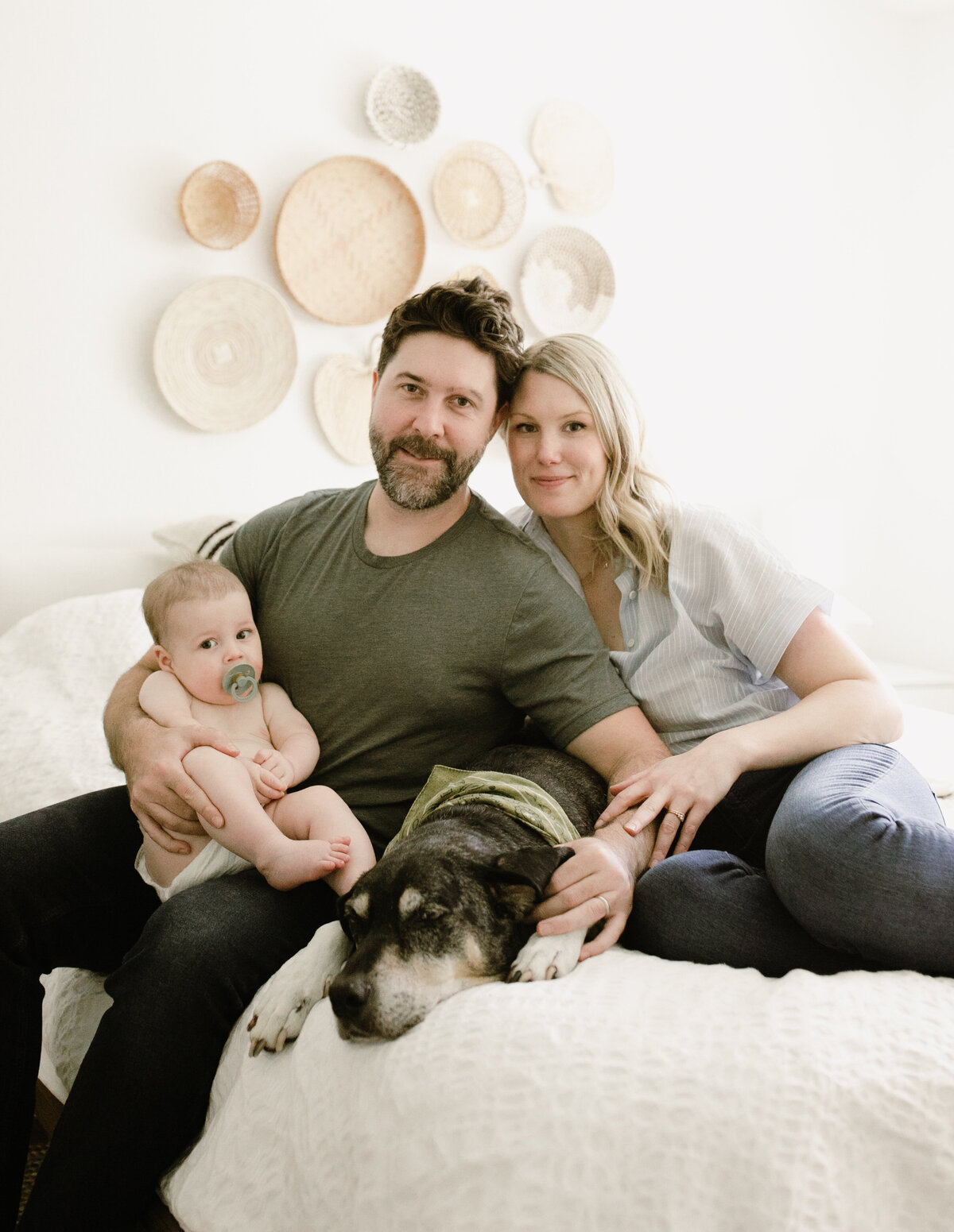 Mother and father on bed with baby and dog at Austin family photo session