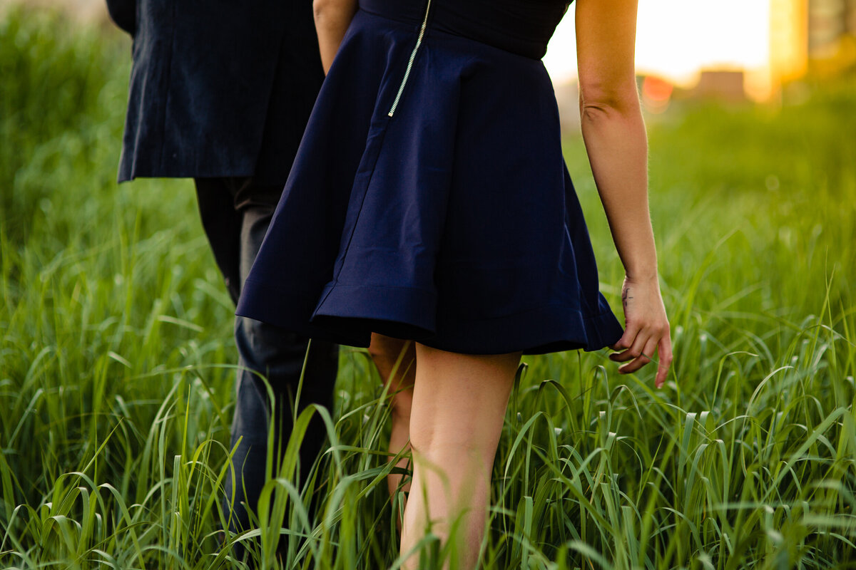 A couple walks hand in hand through a field in Toledo Ohio.  Photo By Adore Wedding Photography. Toledo Wedding Photographers