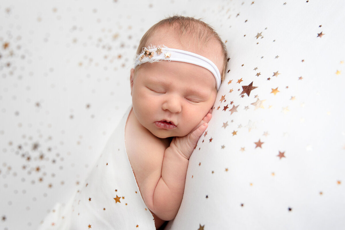 st-louis-newborn-sleeping-baby-swaddled-in-white-starry-blanket-with-matching-starry-white-headband