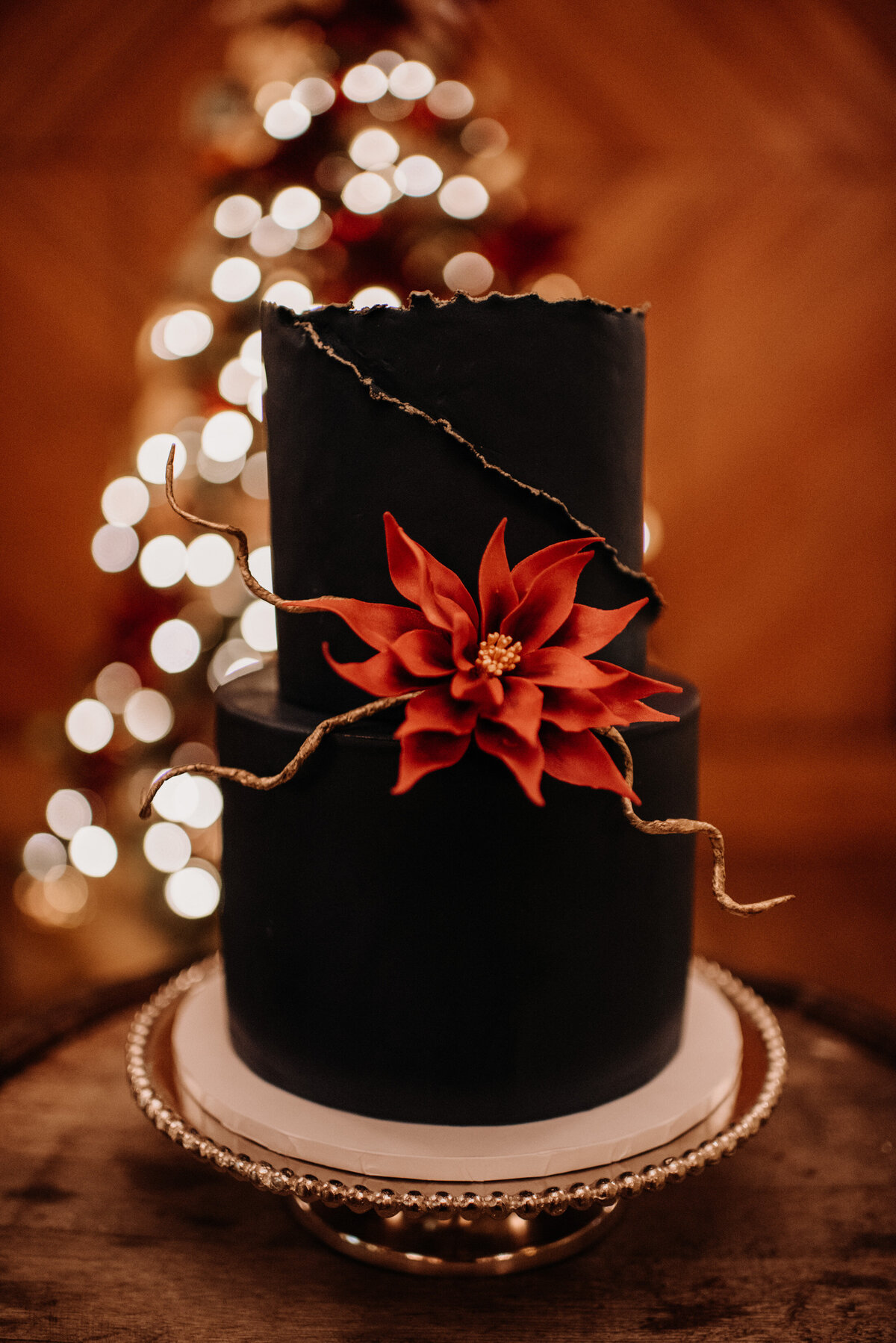 Navy Christmas wedding cake with gold details and sugar poinsettia flower