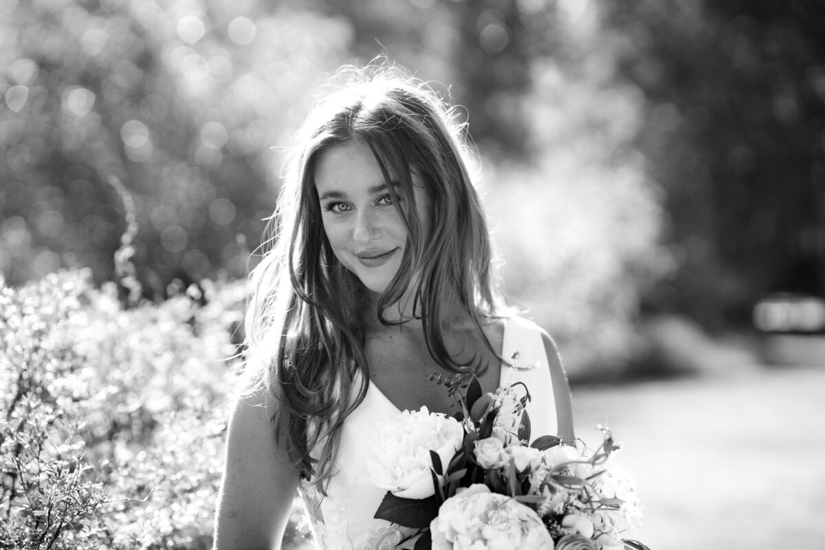 A beautiful black and white image of a pretty brunette, holding her bouquet of flowers,