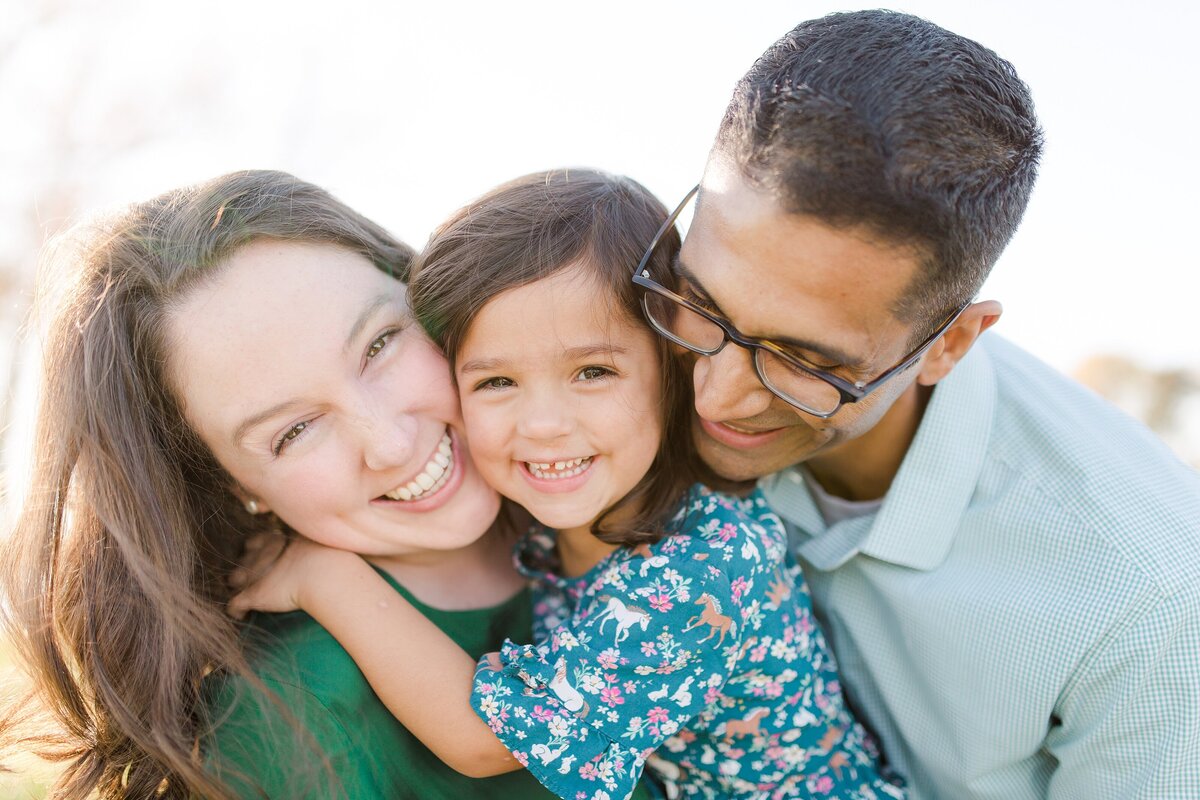 A mom and dad hugging their daughter at a family photo session in Lexington KY.