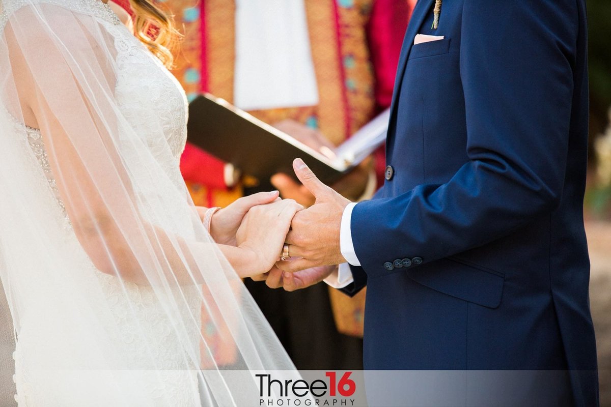 Bride and Groom hold hands while facing each other during ceremony