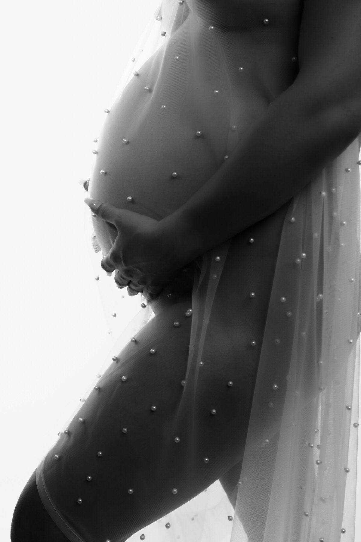 black-and-white maternity portrait of a woman draped in a delicate pearl-studded veil