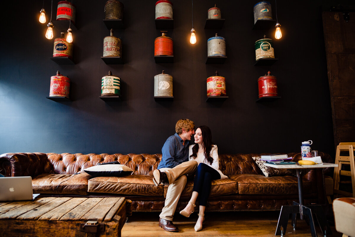 A couple sits on a sofa in a coffee shop in Toledo Ohio.  Photo By Adore Wedding Photography. Toledo Wedding Photographers