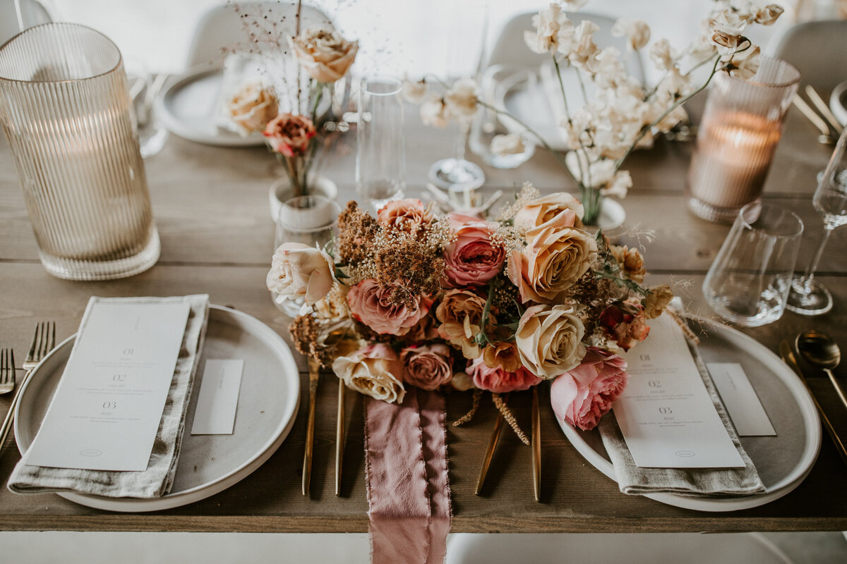 A bouquet of blush and ivory flowers set with white rectangular place cards atop a linen napkin and white plate.