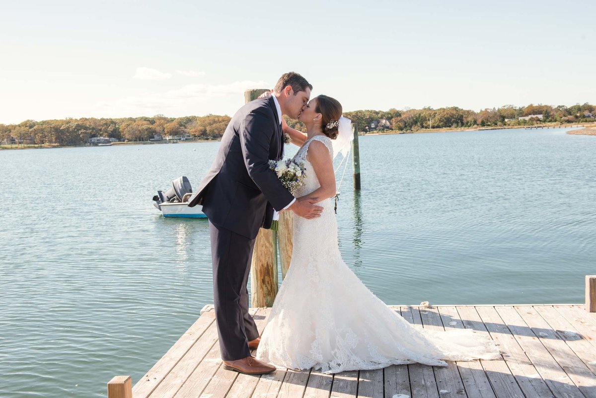 Bride and groom kissing on dock at The Ram's Head Inn