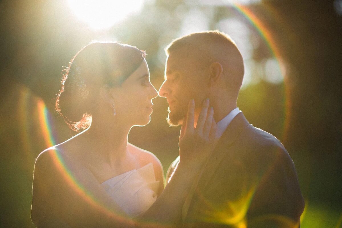 A couple shares a tender moment in a sunbeam, their faces illuminated by the warmth of the light