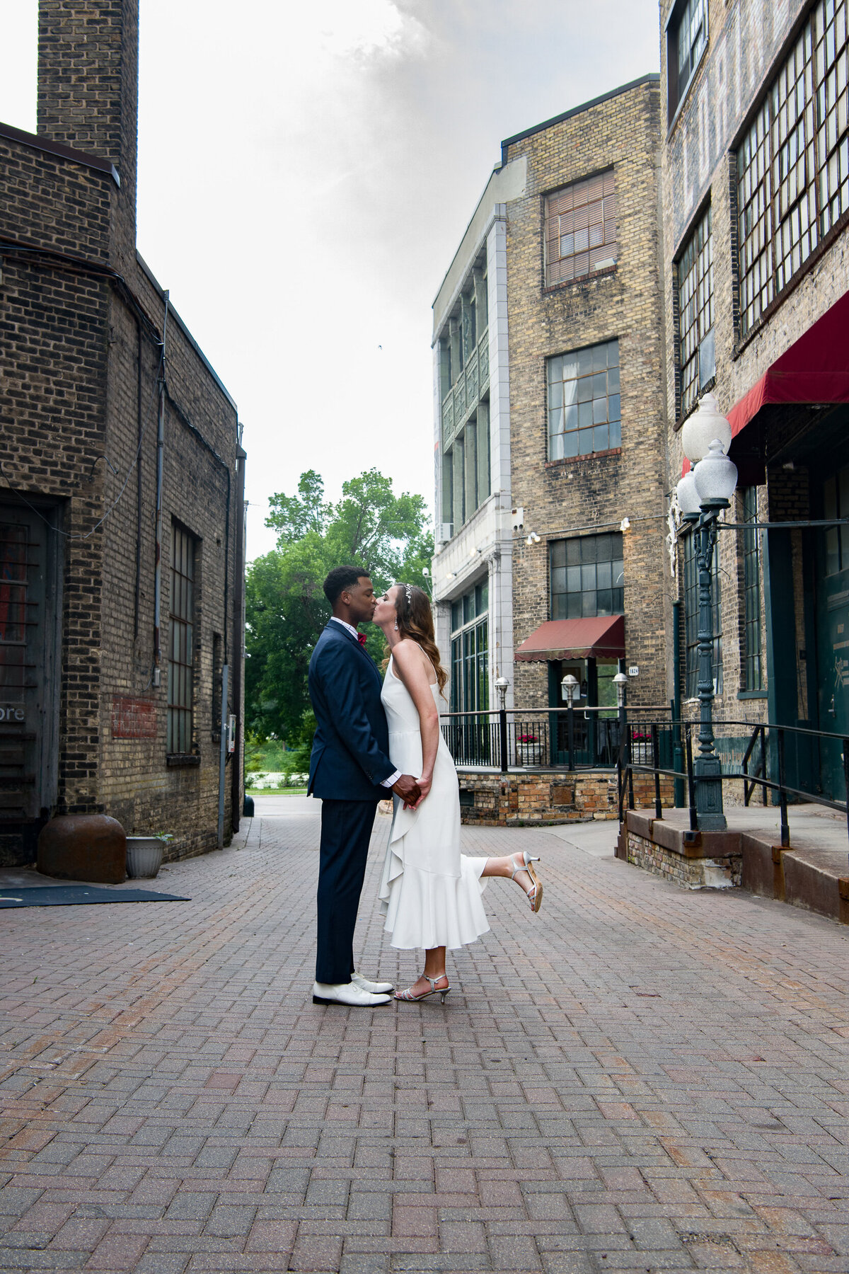 Black groom and bride kiss in alley in Minneapolis, Minnesota.