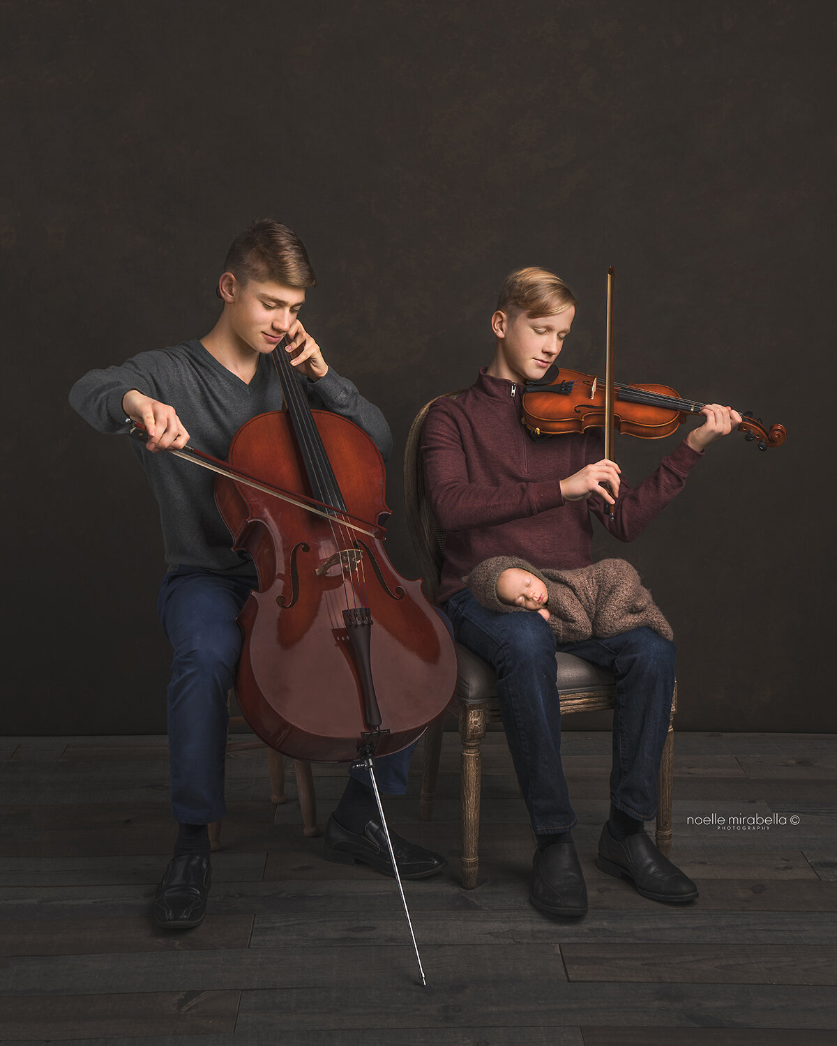 Teen boys playing the violen and cello with baby on their knee.