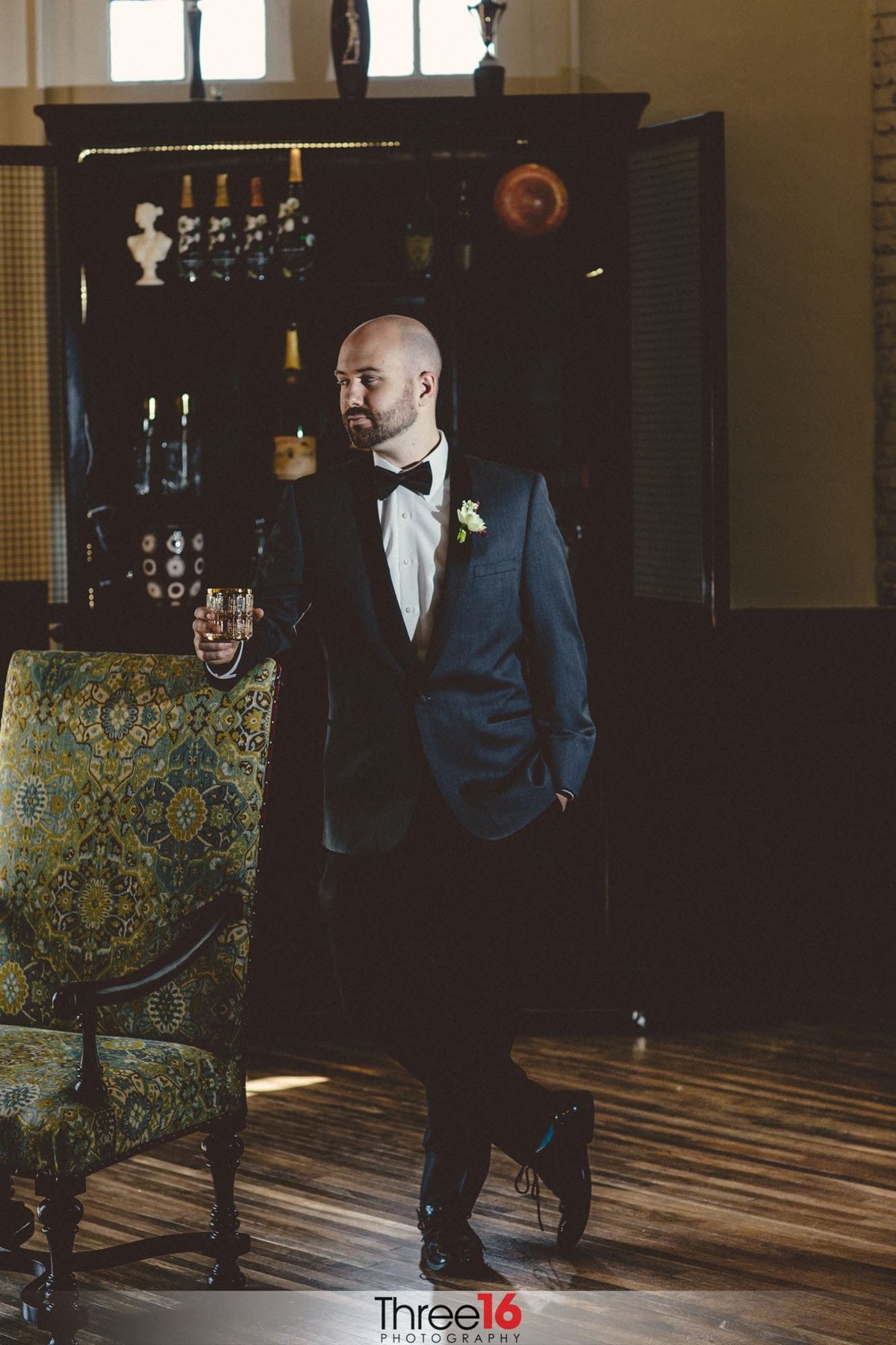 Groom poses in the lounge area holding a drink