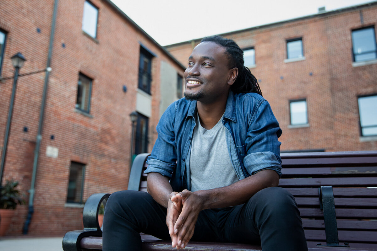 A-Black-Baltimore-man-poses-for-headshots-in-Baltimore-Maryland-while-smiling-peacefully-in-Fells-Point