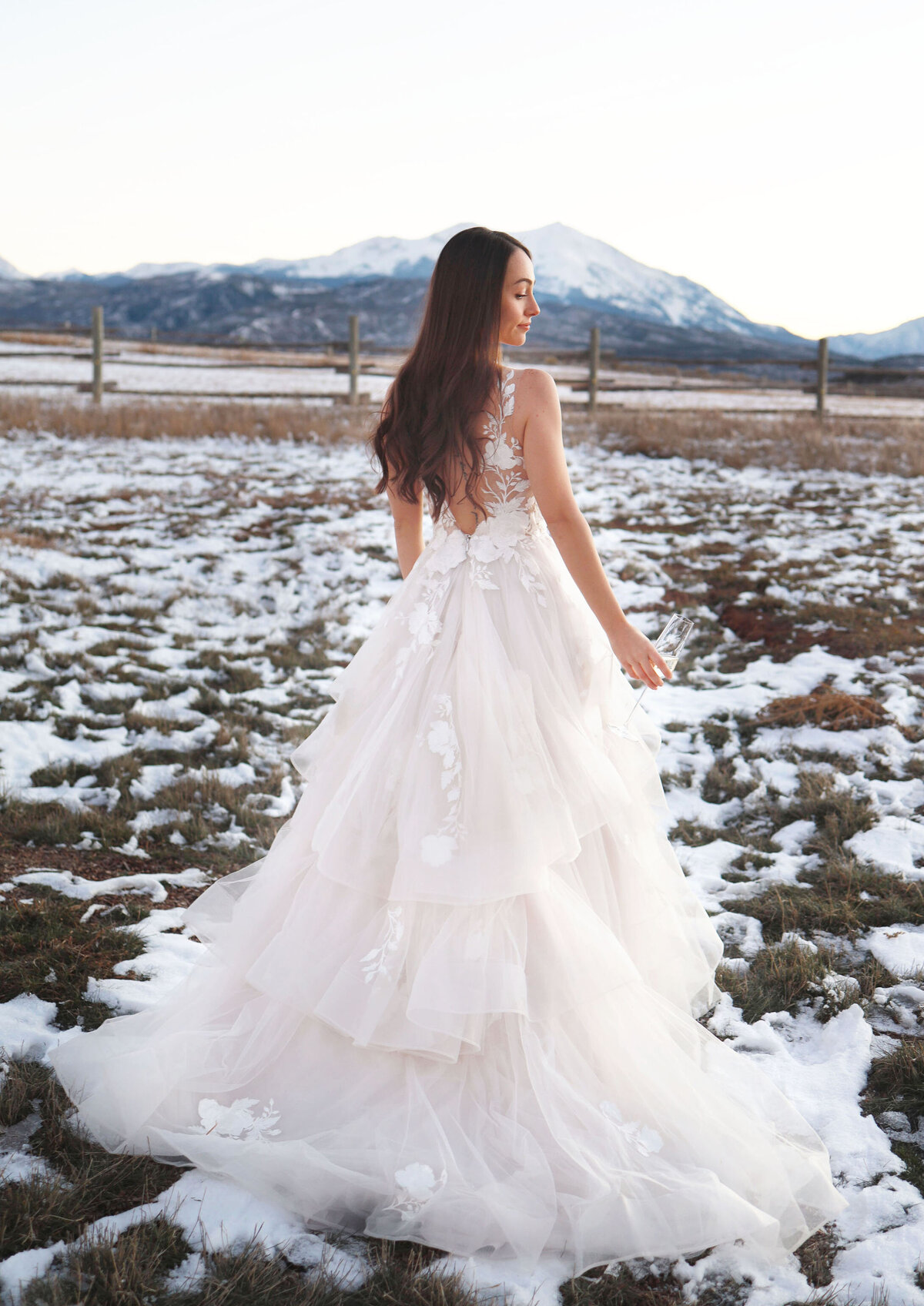 Bride in a gorgeous white wedding dress, having a moment alone in the snowy mountains.