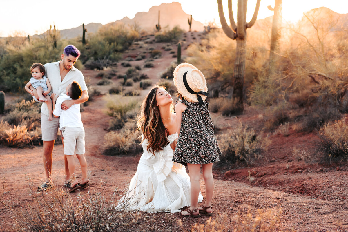 family hugging and kissing in the desert at sunset
