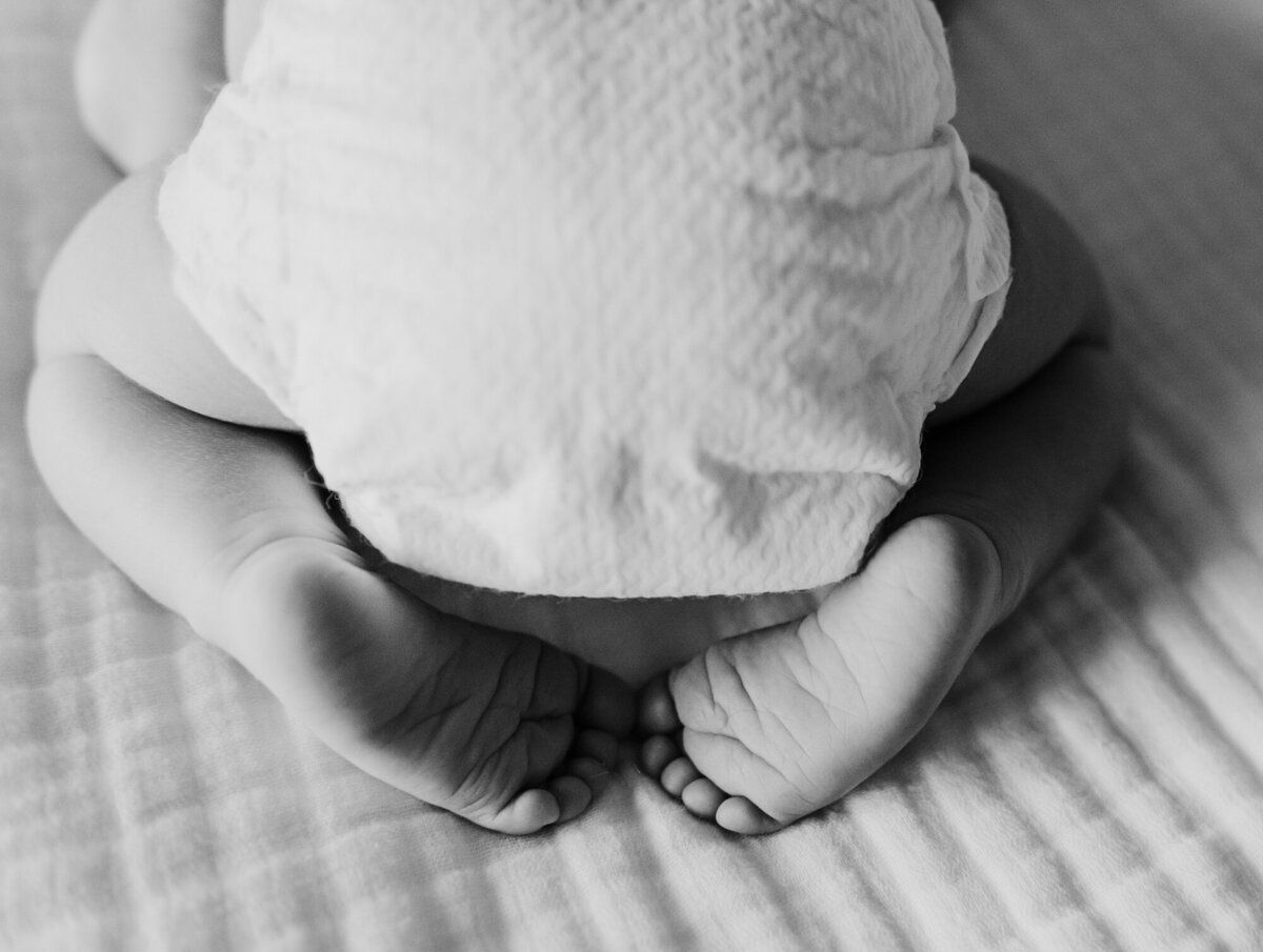 Newborn Photographer, Baby in a diaper with feet sticking out.