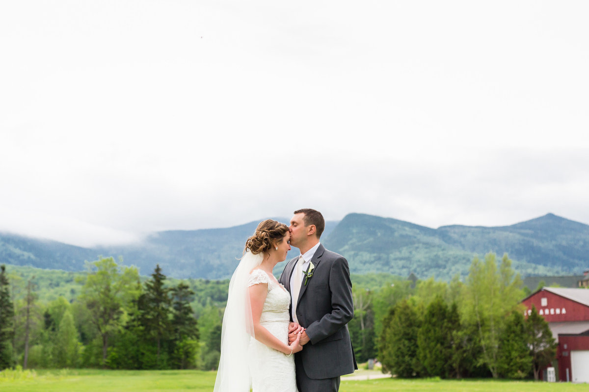 The couple share a moment in front of the mist covered White Mountains after their wedding at Waterville Valley Resort in New Hampshire