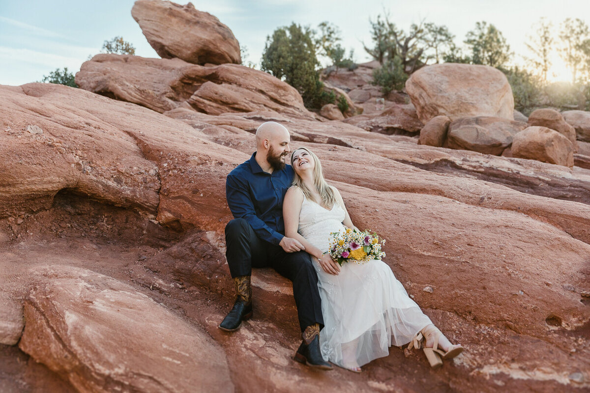 bride and groom eloped at garden of the gods and are laughing and laying with each other