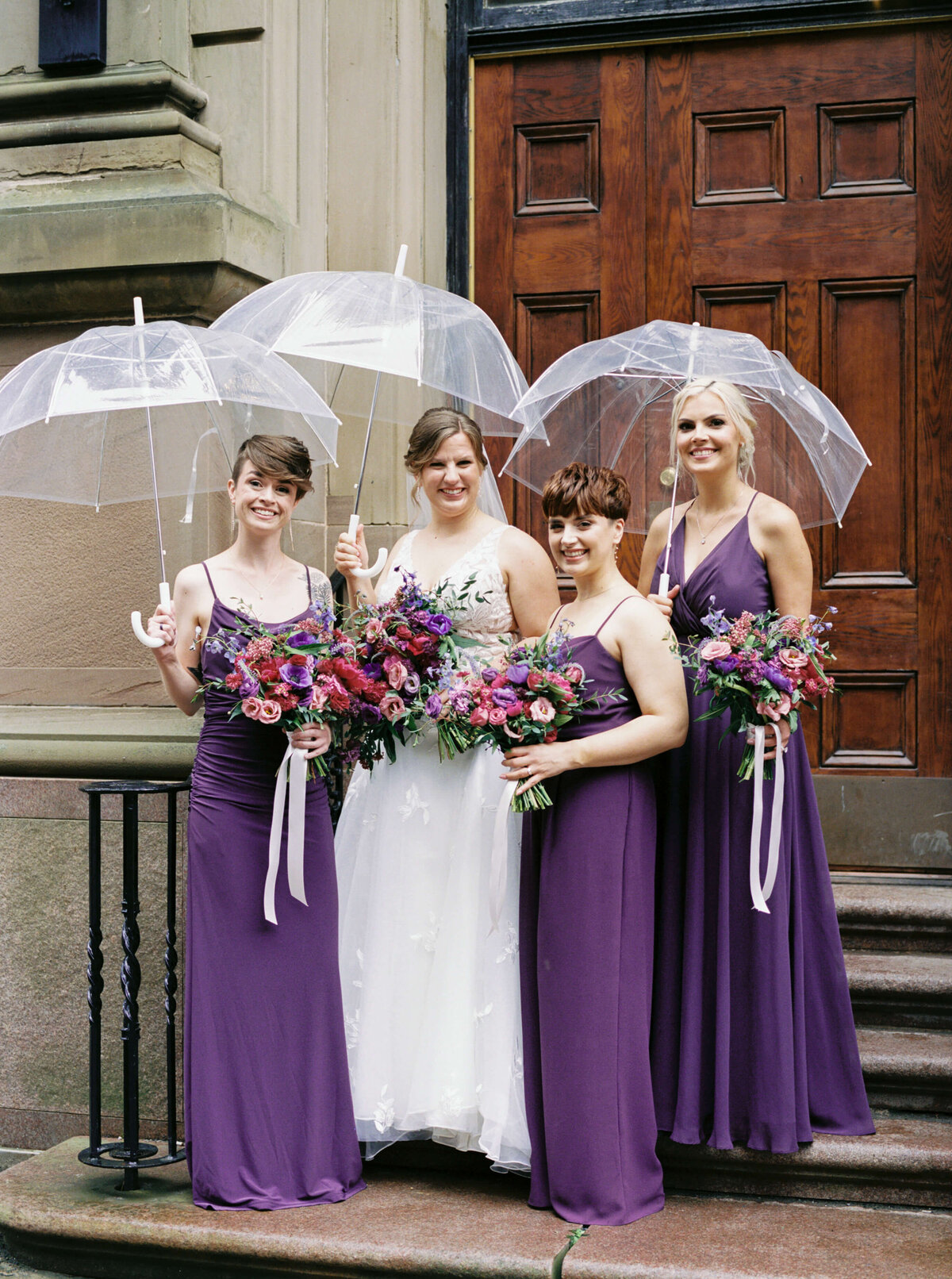 Bridesmaids wearing purple dresses with bride standing outside the Halifax Club in Nova Scotia