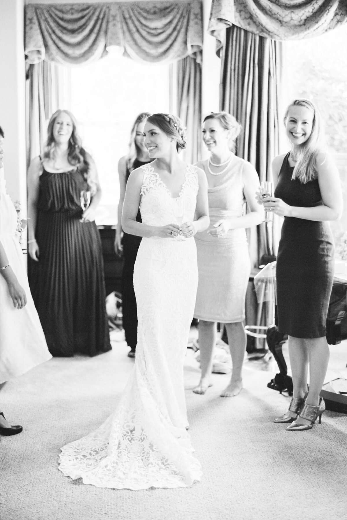 Bride shows her dress off to her wedding bridesmaids.