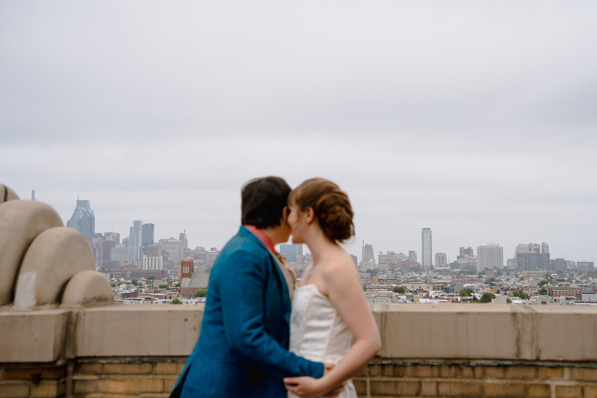 A couple with their arms around each other's waists looking out over a city skyline.