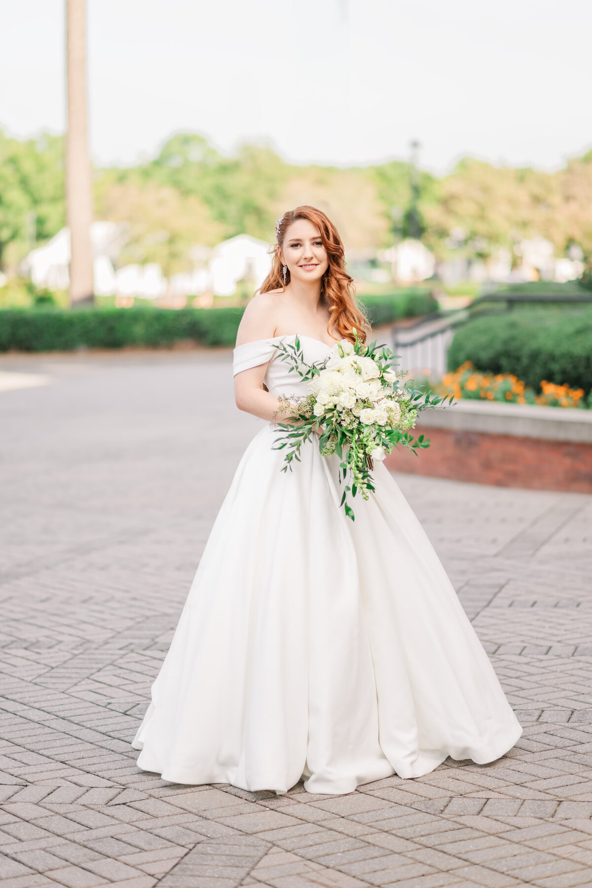 A bride standing in a pavillion in Cary holding her white wedding bouquet during a fall afternoon enjoying her Raleigh wedding photography session by JoLynn Photography