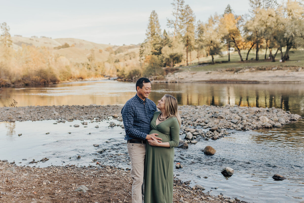 Couple stands embracing by the River in Coloma Emily Woodall Photography