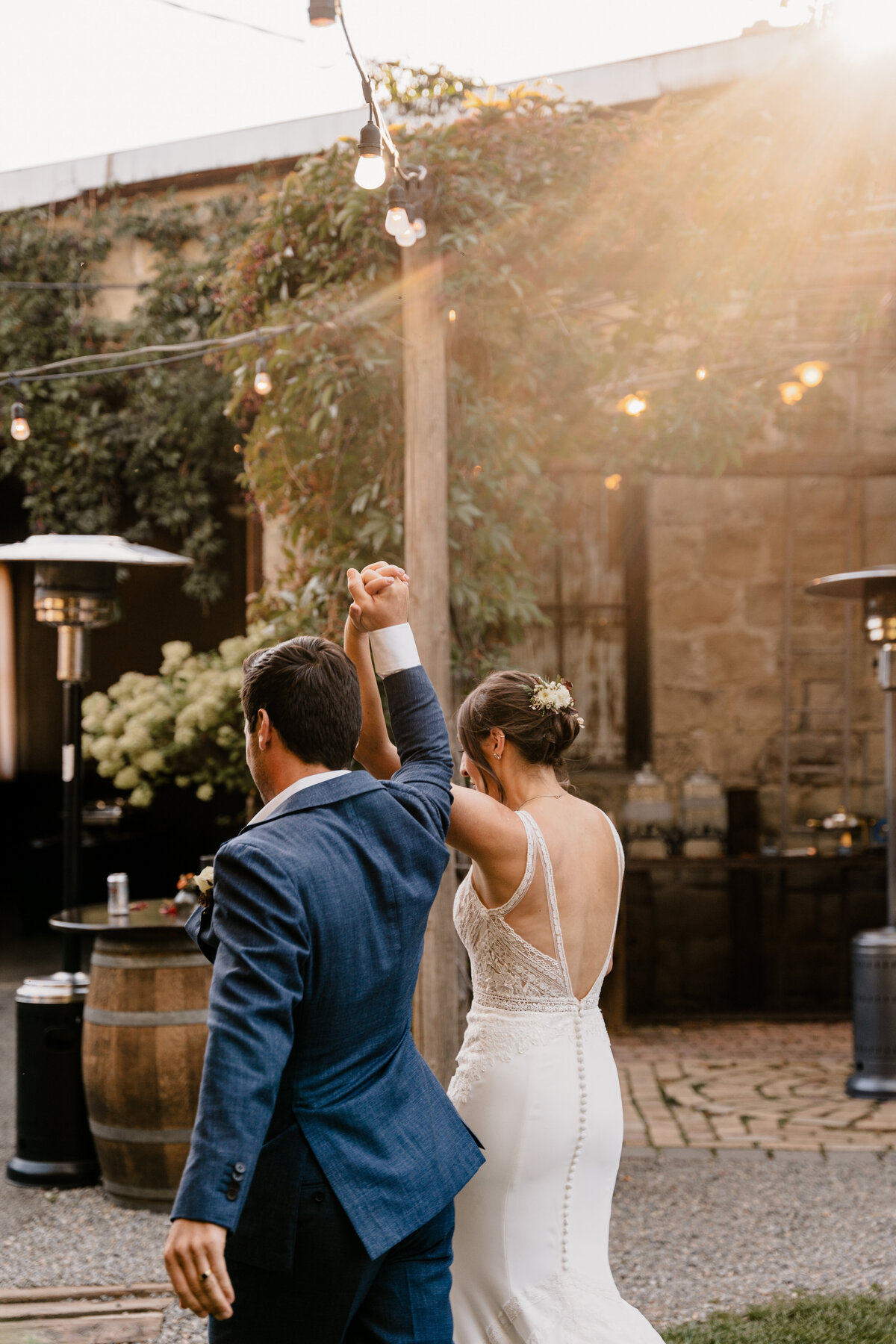 The bride and groom exit their ceremony, holding hands and raising them up in celebration.