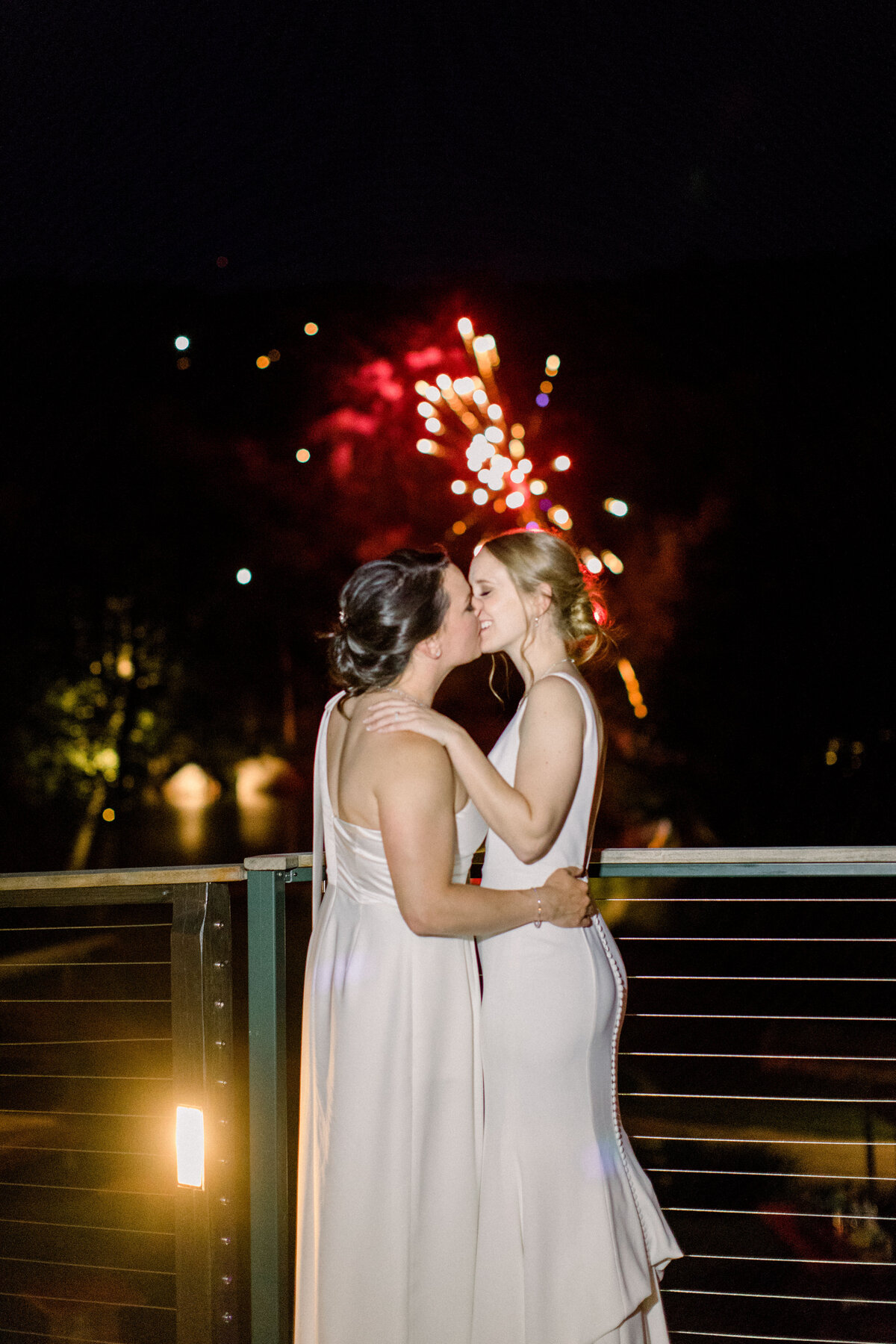 Brides kissing with fireworks behind at Lakefalls Lodge wedding