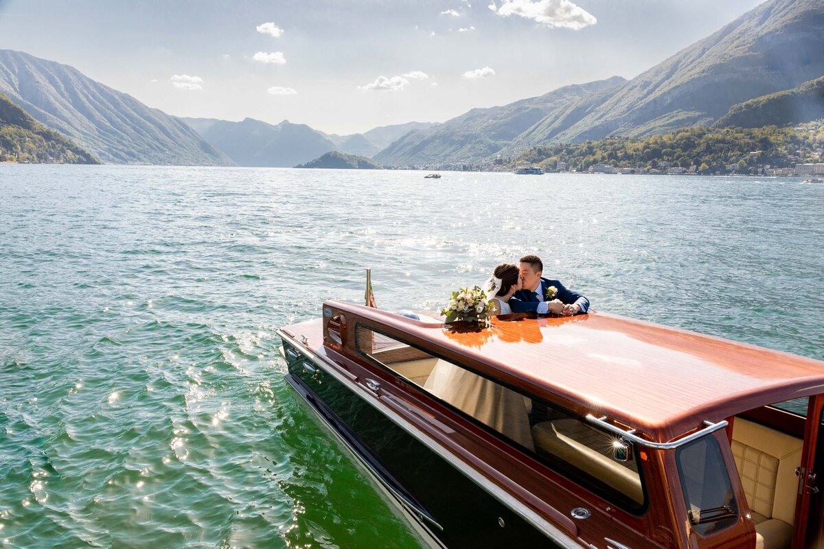 A couple kissing while standing on a small boat.