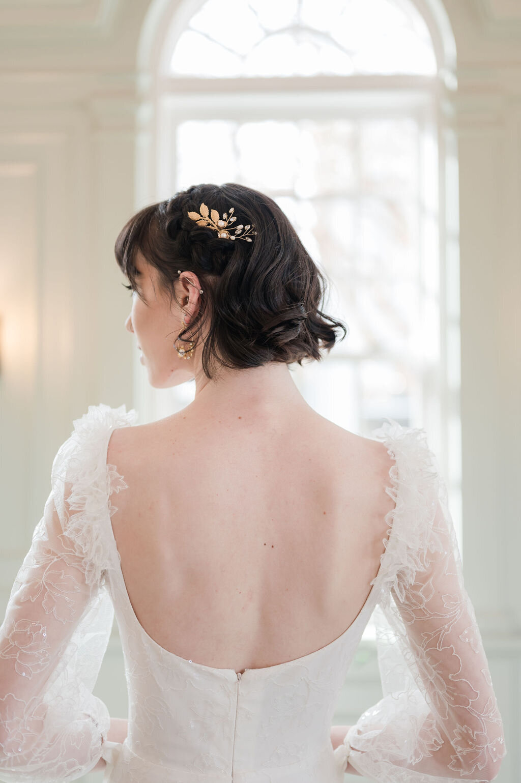 Close-up of the scoop back and 3D flowers on the sleeves of the Gene wedding dress style. The gold floral hair comb is by Emma Katzka.