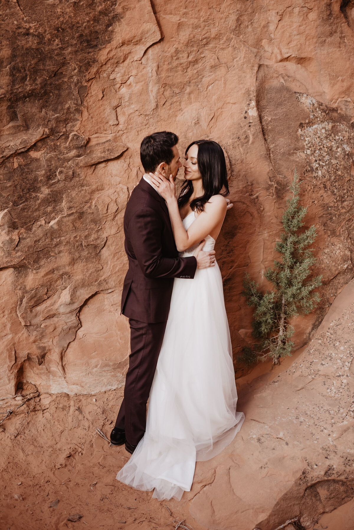 Utah elopement photographer captures bride holding groom's face during arches national park wedding