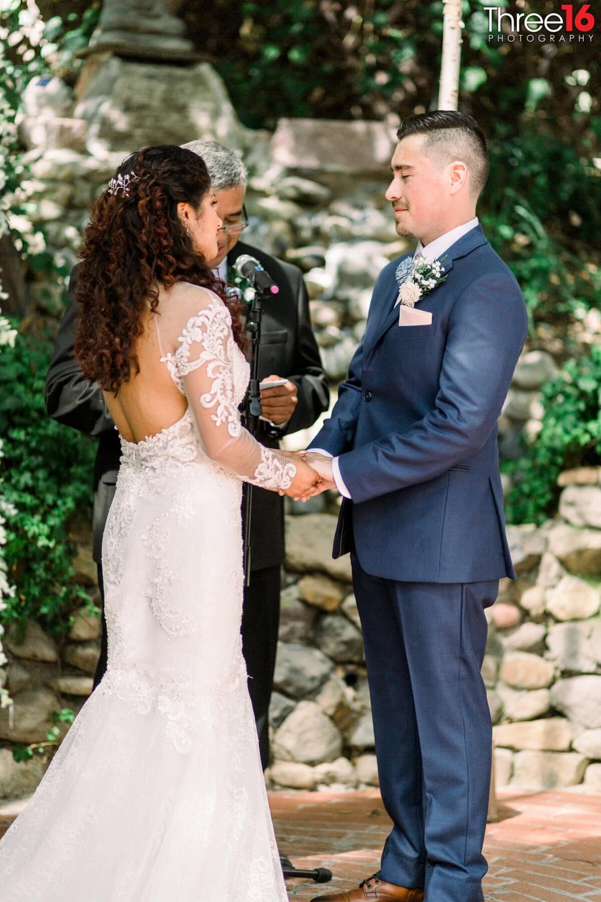 Bride and Groom face each other while holding hands as the officiant performs the ceremony
