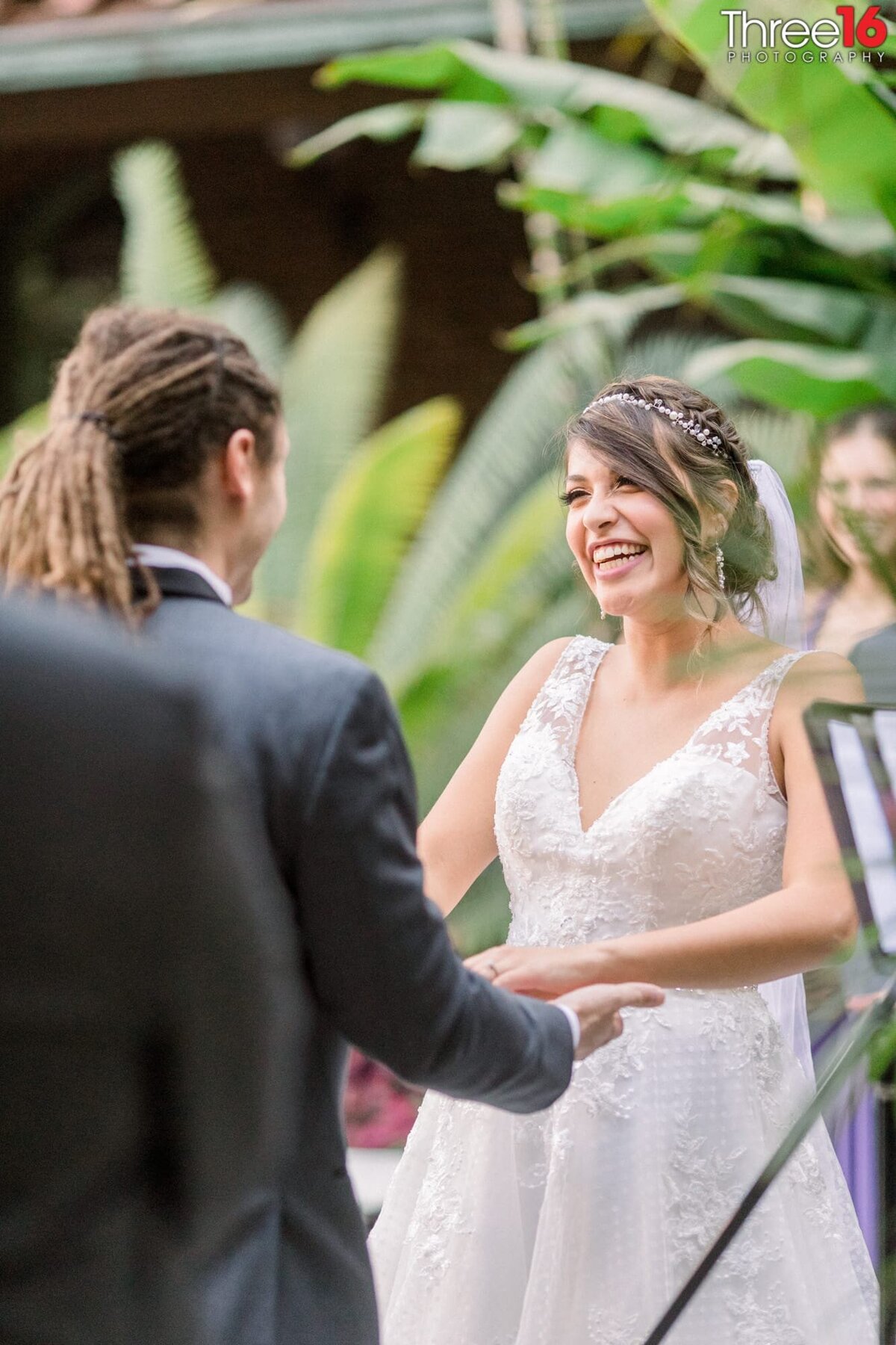 Bride gives her Groom a really big smile as she takes his hands while standing at the altar