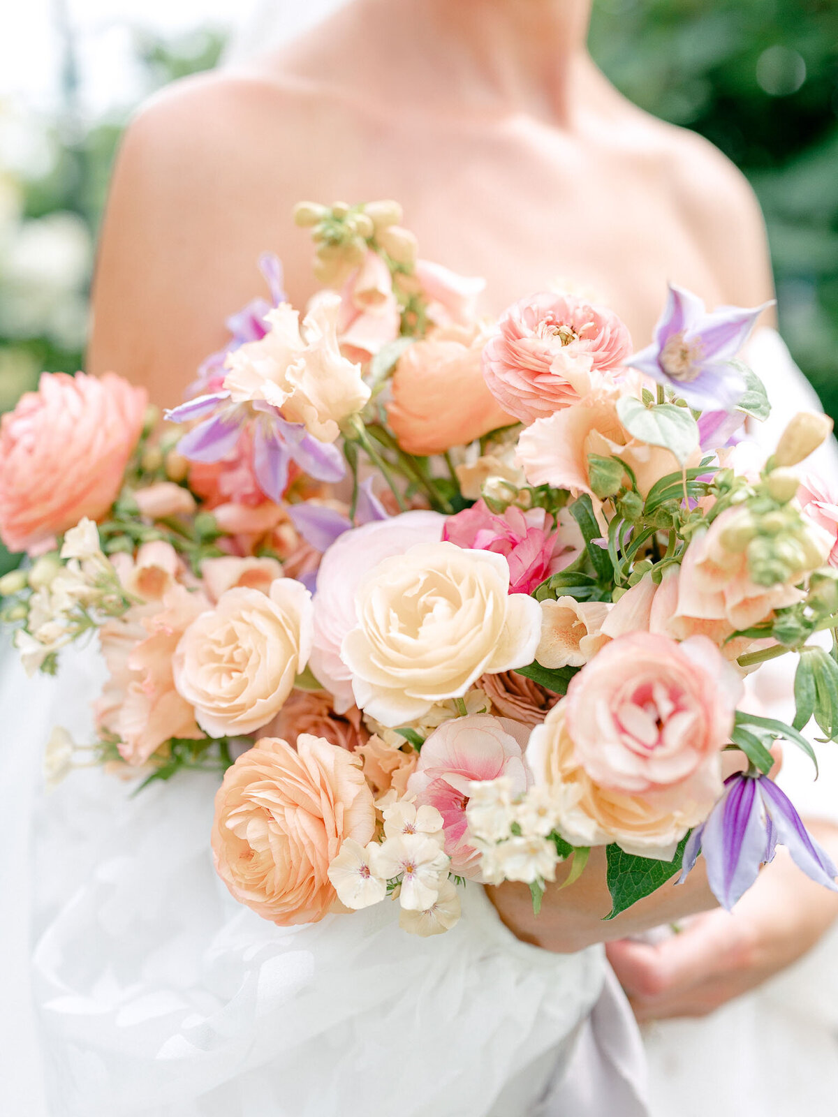 Close up of bride's peach, purple, and pink floral bouquet