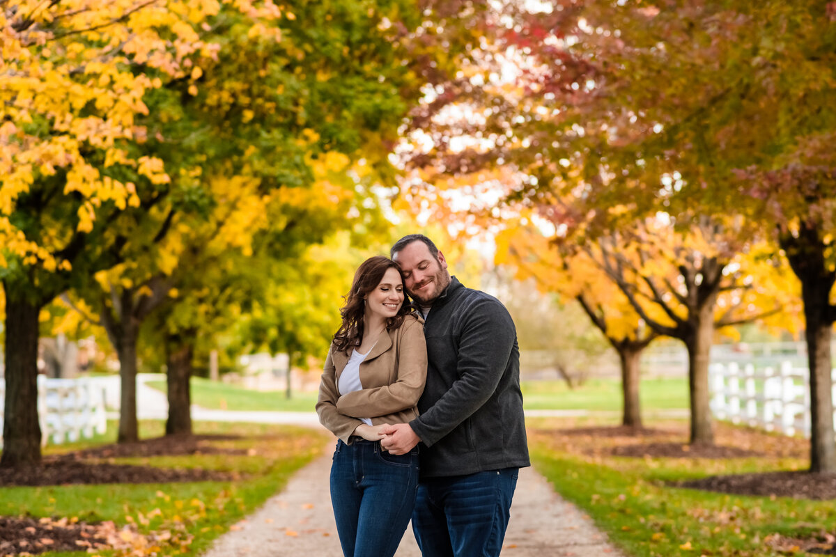 A couple embrace in front of fall colors