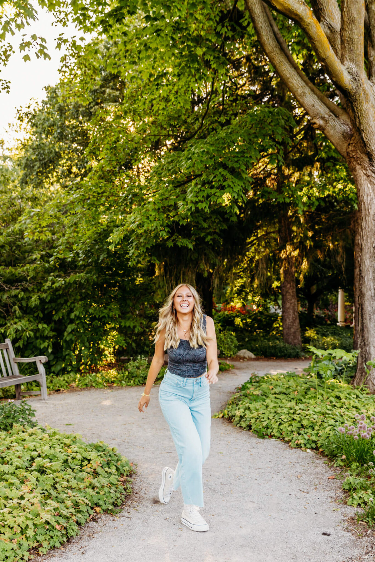 beautiful teen girl laughing as she walks along a garden path during her senior photography session