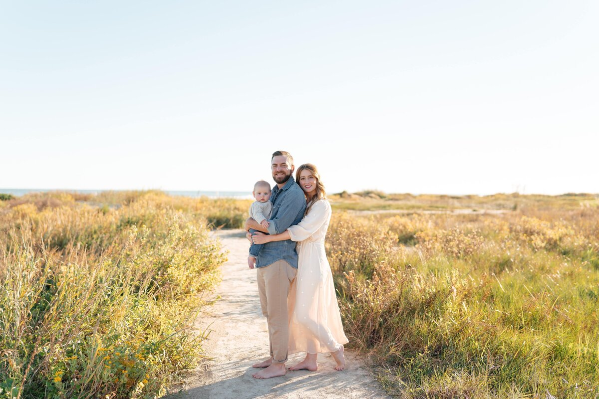 Mother and father embracing baby in a field