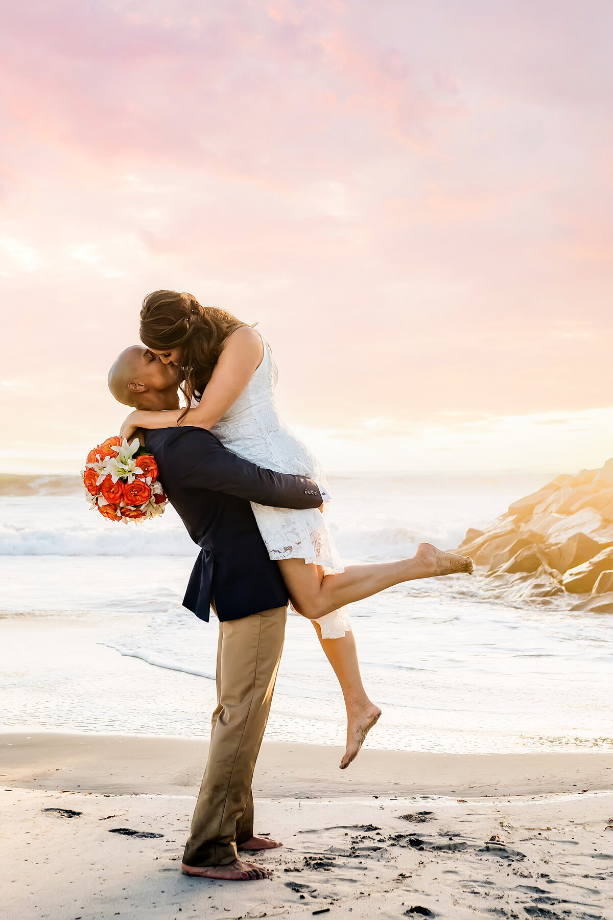Bride and groom kissing on the beach in Carlsbad