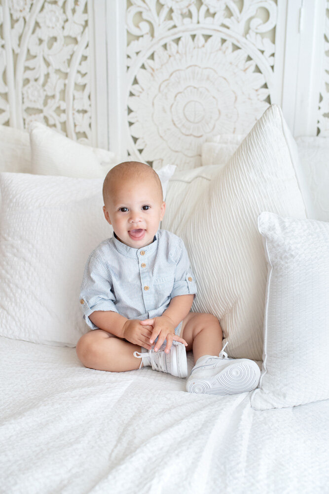 Family session of little boy seated on a bed