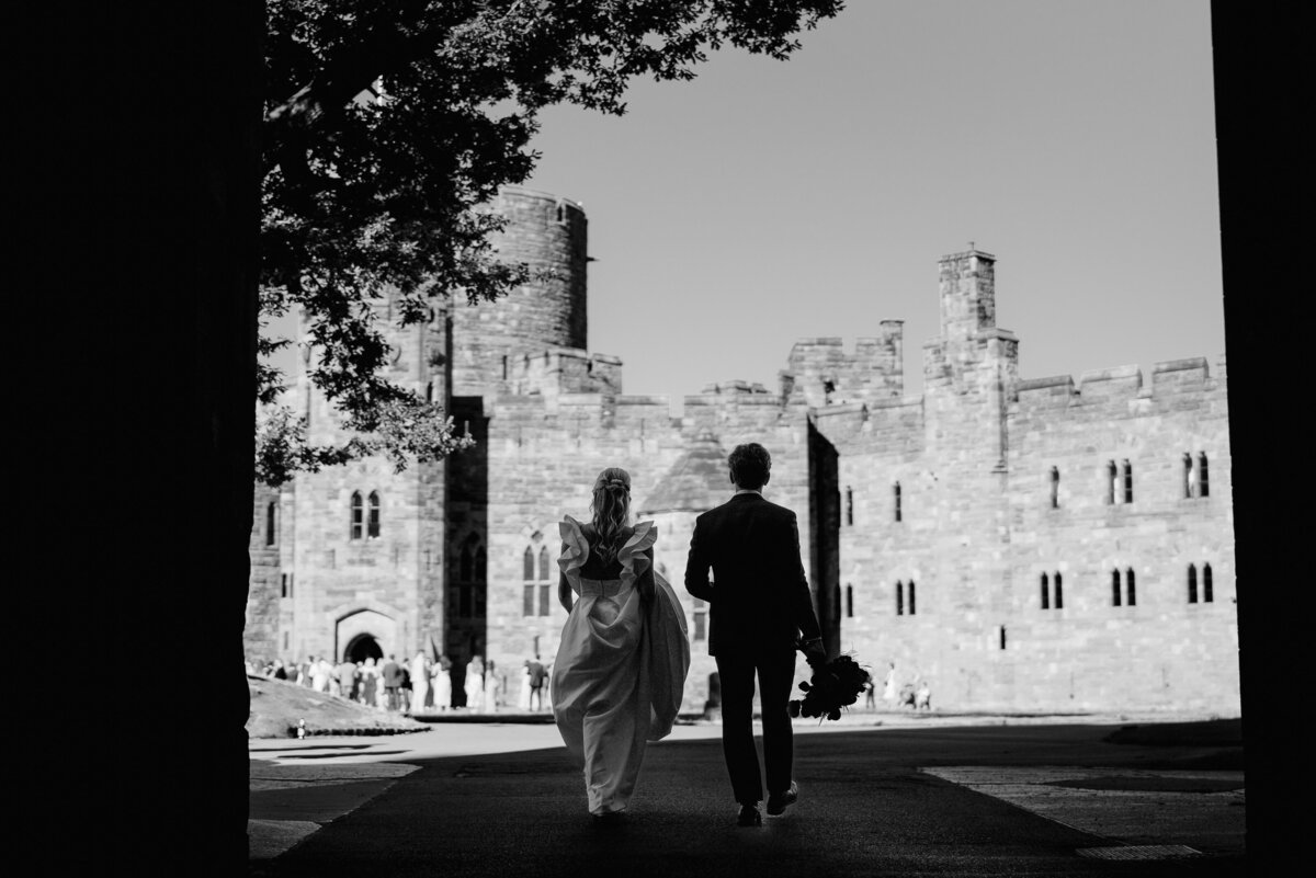 bride and groom walking towards peckforton castle in cheshire