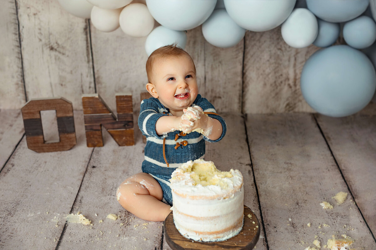 1 year old boy playing with his cake smash cake on his cake smash session