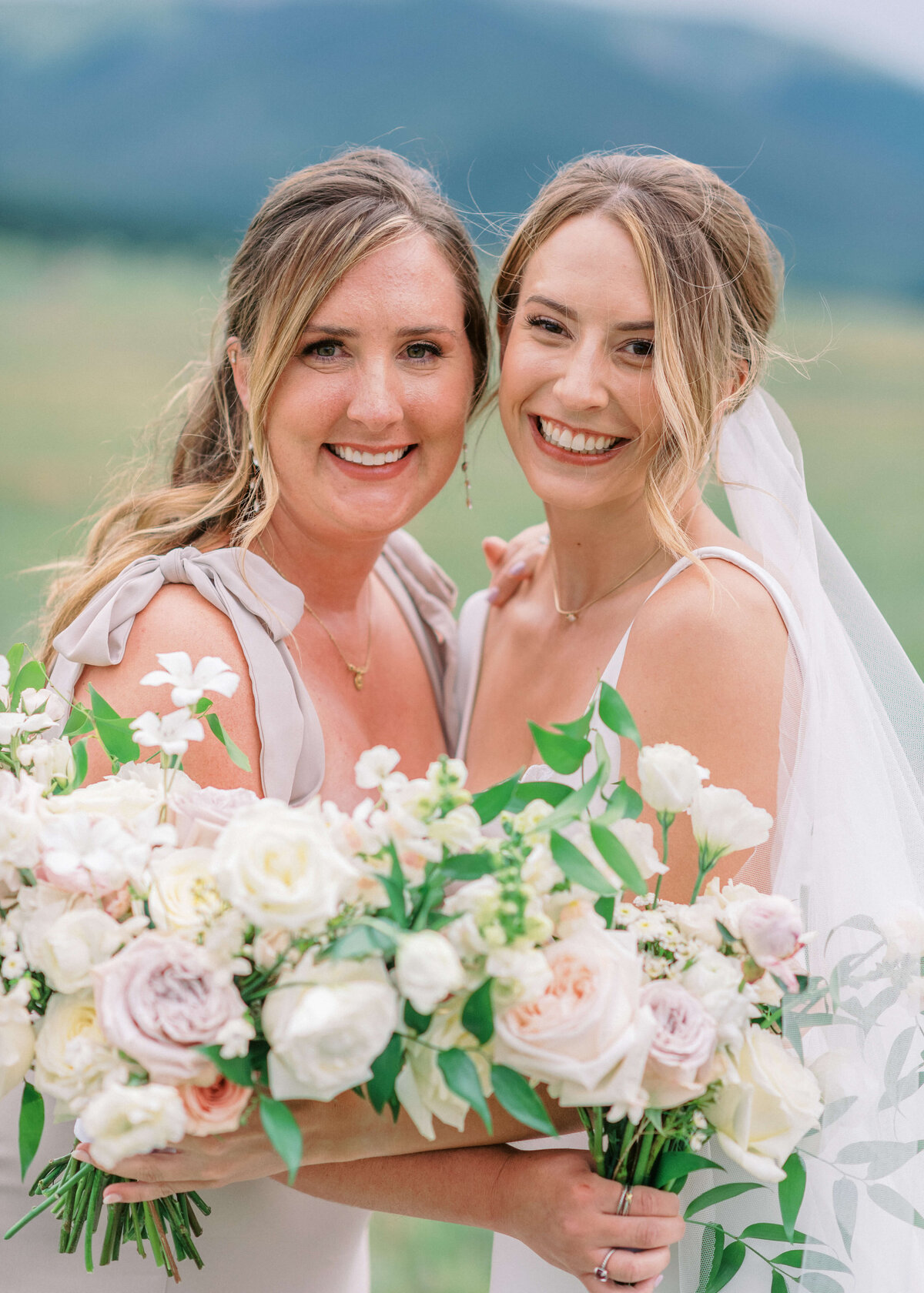 The bride and her maid of honor share a hug and smile at the camera of Virginia wedding photographer