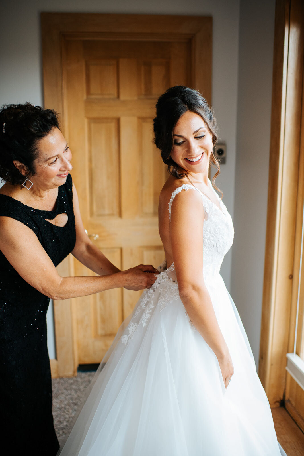 mother of the bride helping bride zip her wedding dress at mountain top inn vermont